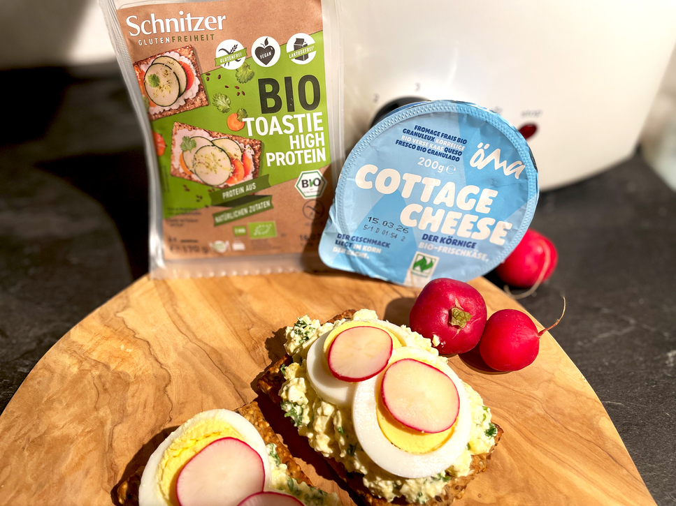 Auf dem Bild sind glutenfreie Toastbrote mit Cottage Cheese und Radieschen sowie eine Packung Bio-Toast und eine Schale Cottage Cheese zu sehen.
